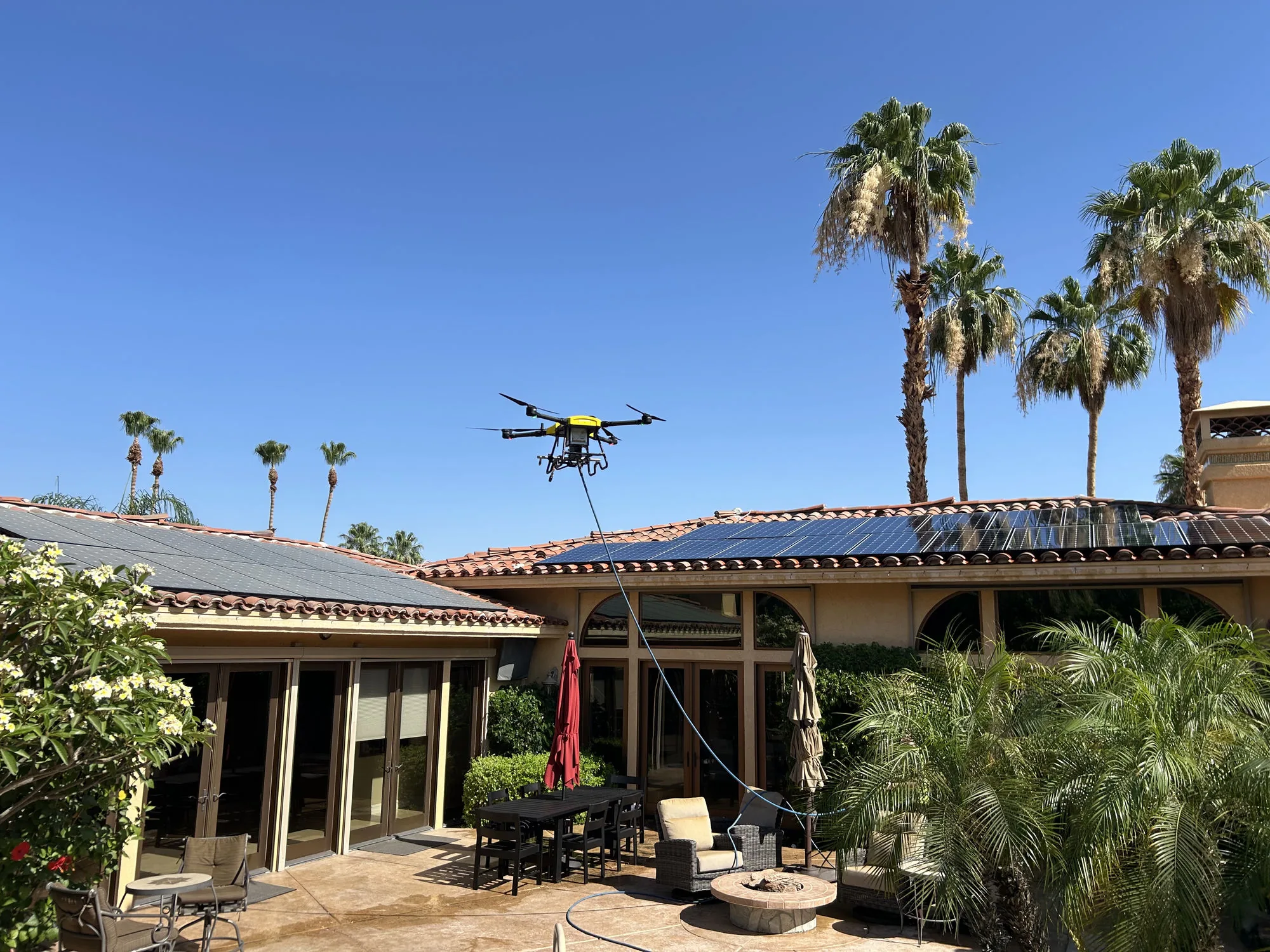 Drone Power 1 aircraft holding station above a tile-roof array mid-pass