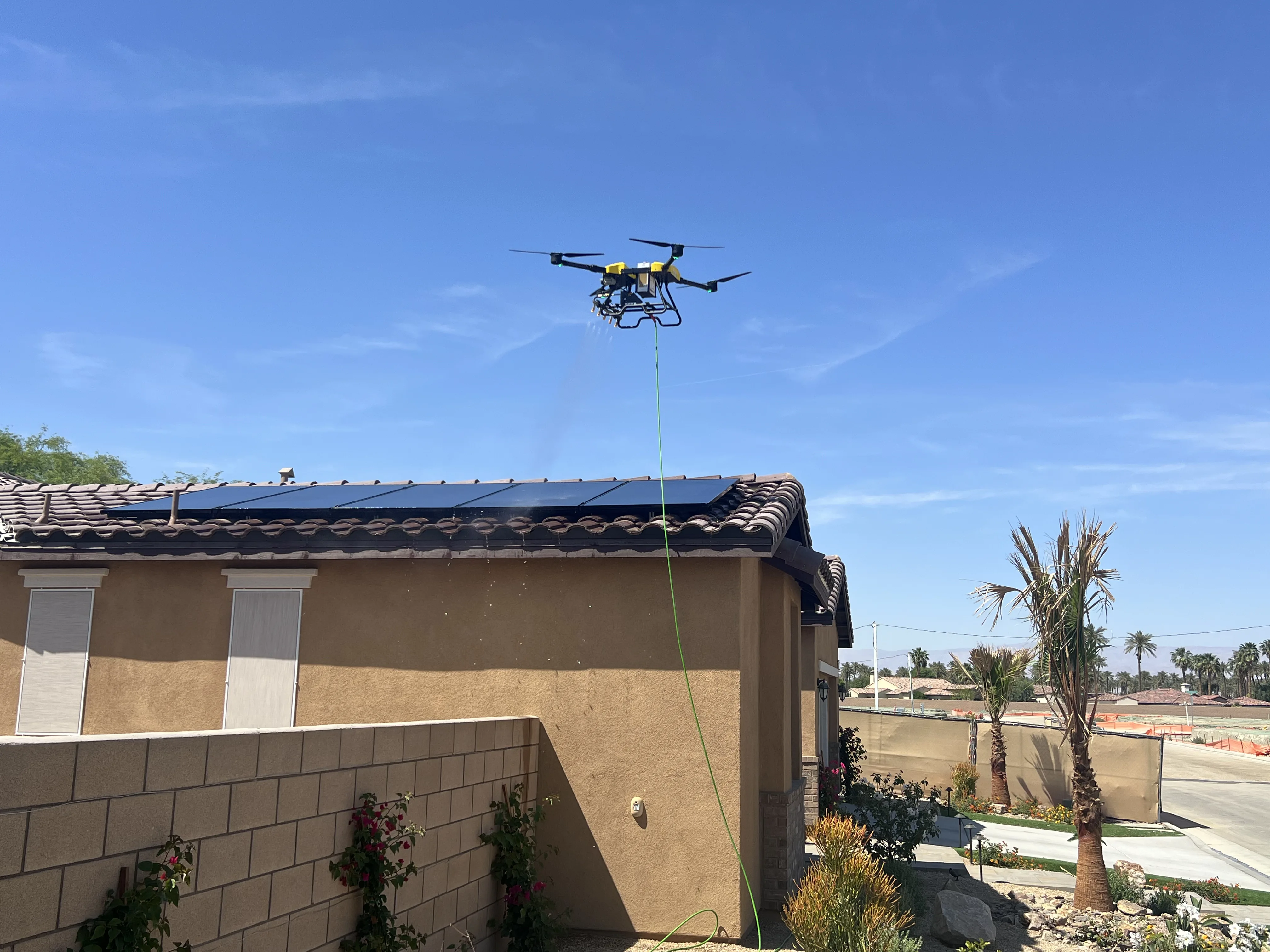 Mid-altitude approach with the drone on station above the roofline — clean sky, clean panels.