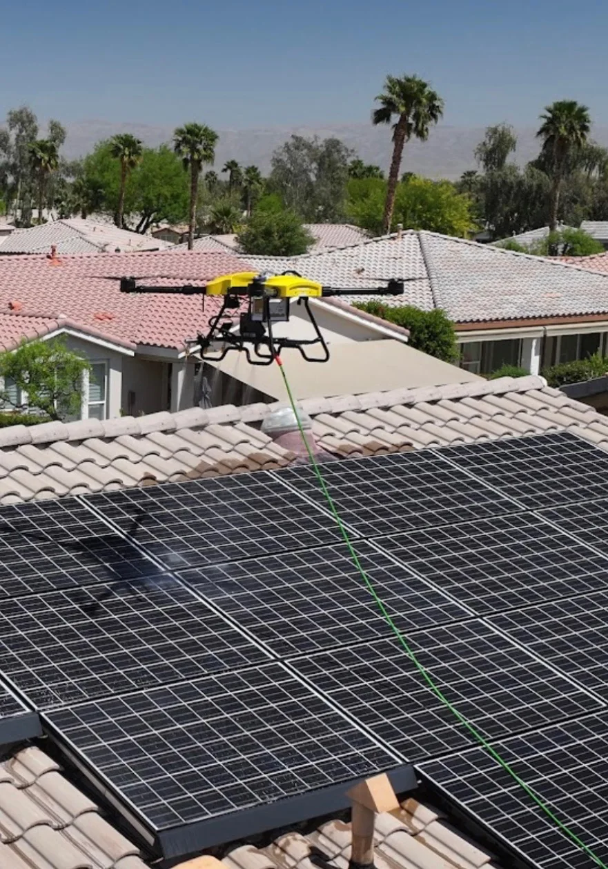 Drone holding above a desert residential array with palms behind — the Coachella Valley standard view.